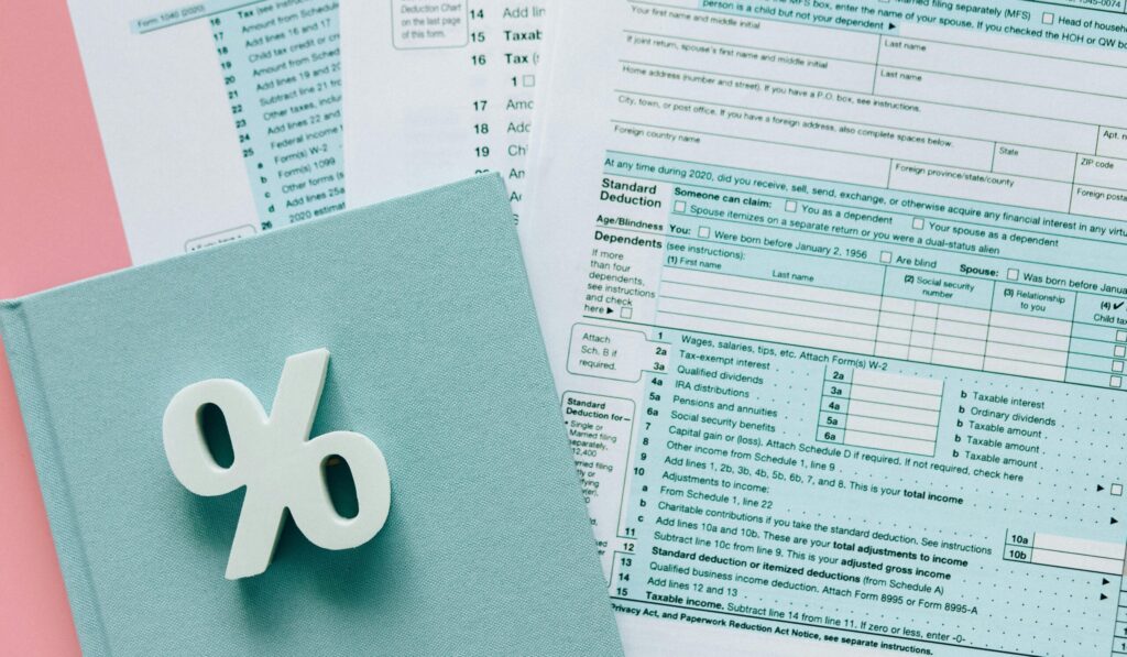 Tax documents with a percentage symbol on a pink and blue desk setup, emphasizing finance.